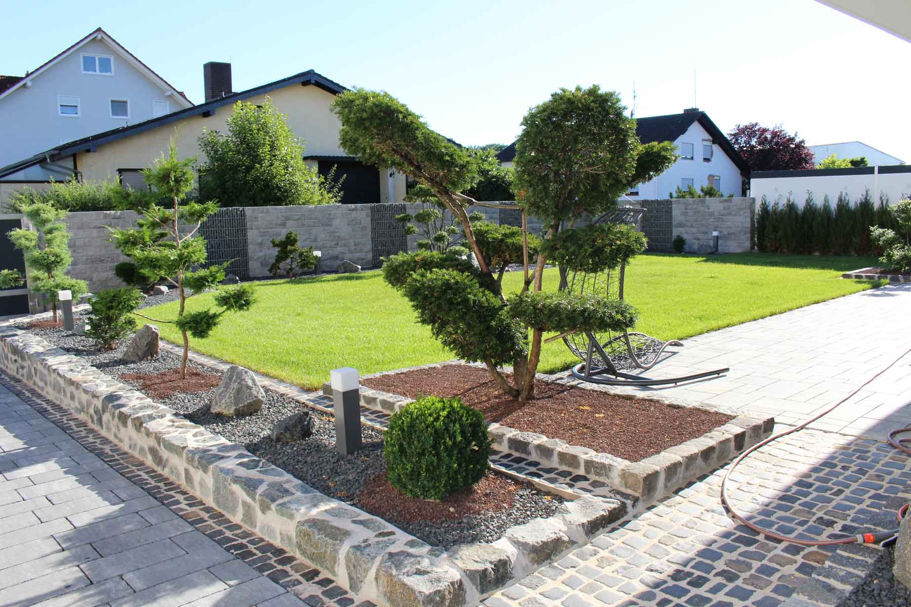 Pflasterarbeiten im Garten mit Rasen und Bäumen